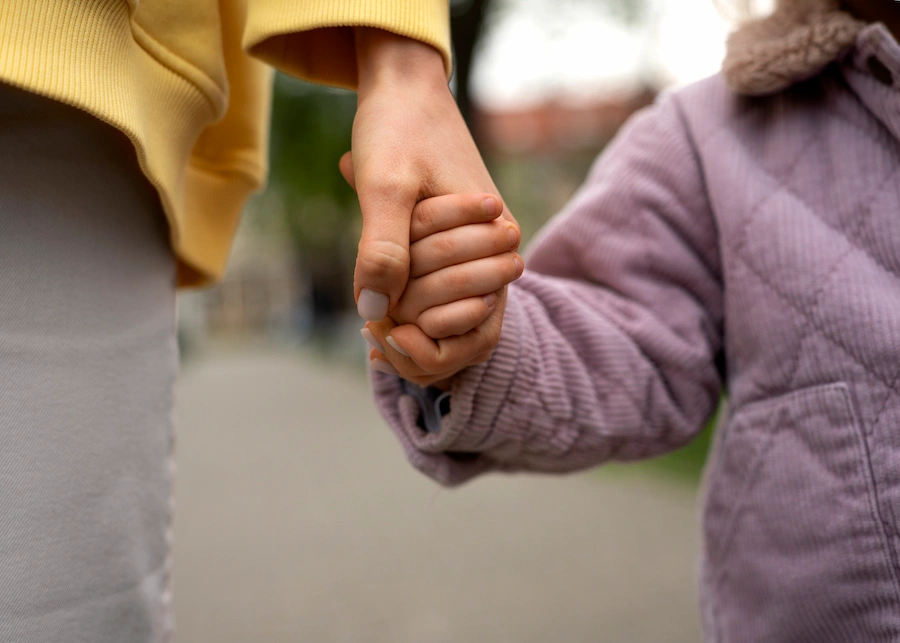 Mãe a acompanhar de mão dada a filha, criança