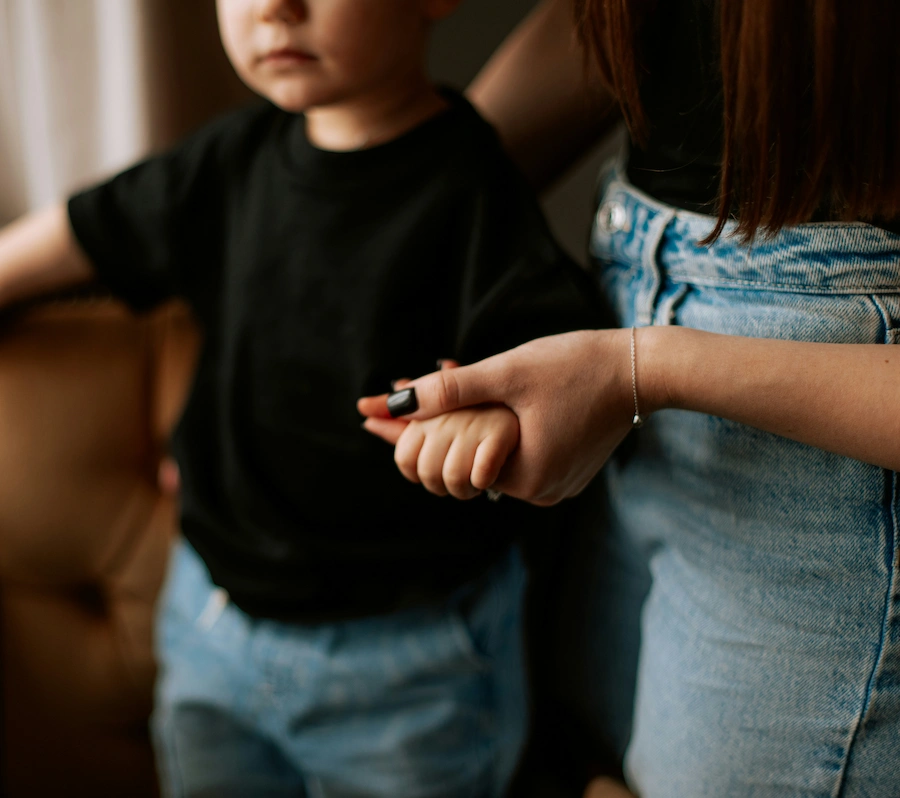 Mãe a amparar o filho, criança, agarrando-o pela mão
